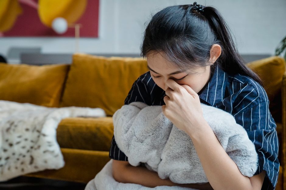 一人で毛布を抱えてつらい表情を見せる女性