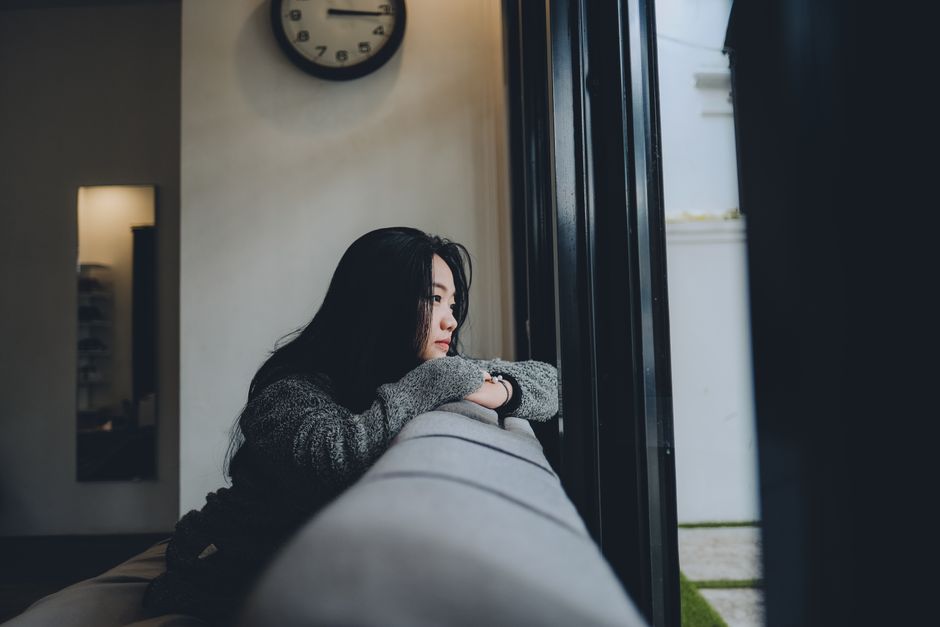 窓の外を見つめながら一人座る女性