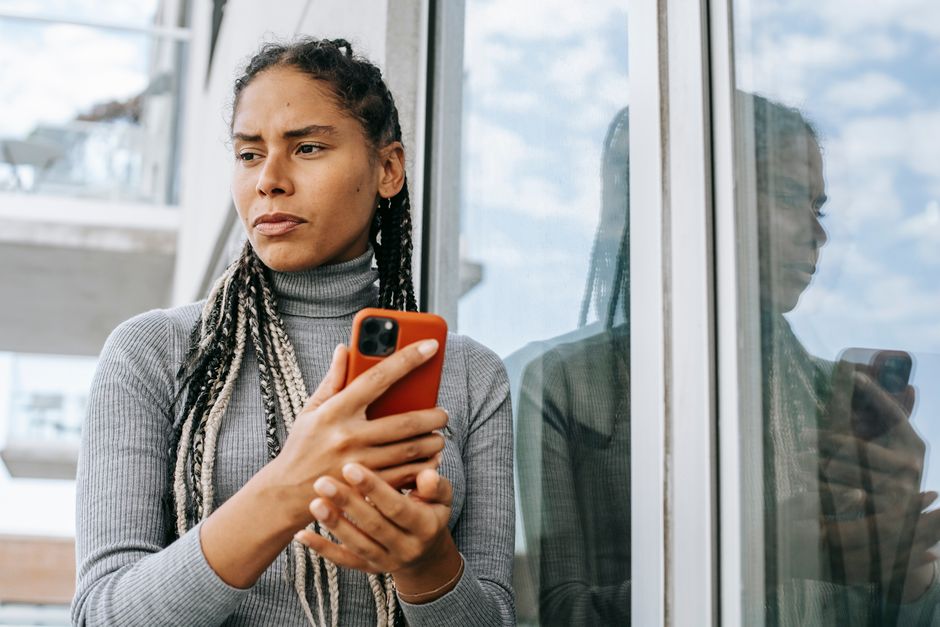 スマートフォンを手に考え込む女性