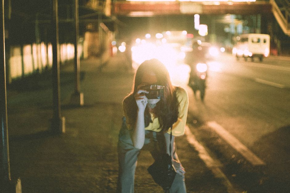 夜間に屋外で慎重に写真を撮る女性