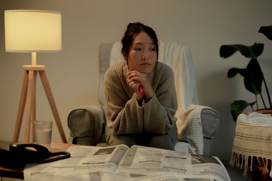 自宅で書類を読みながら不安そうな女性