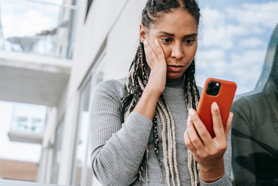 スマートフォンを握りながら不安そうな女性