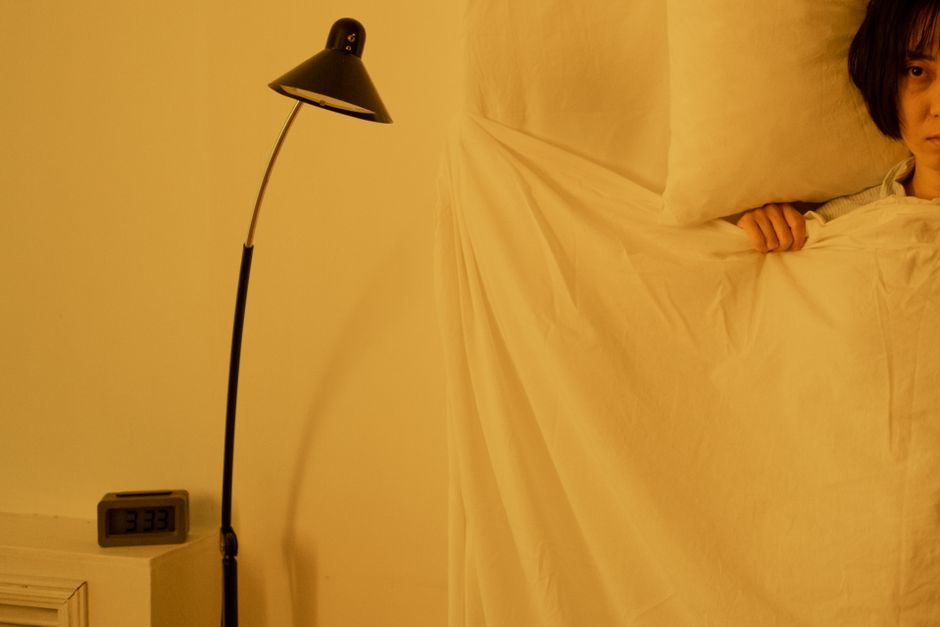 眠れずベッドで悩む女性のイメージ