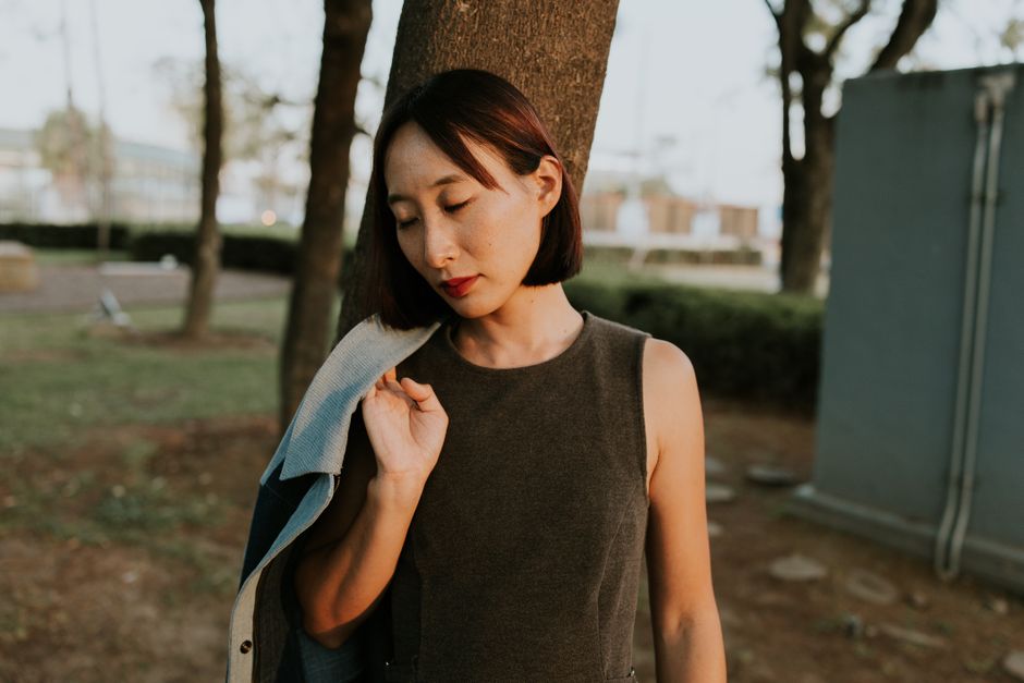 屋外で遠くを見つめて立つ思案する女性